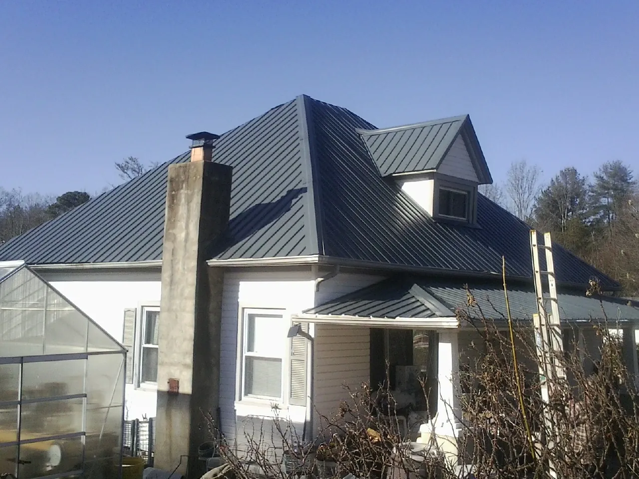 Dark blue standing seam metal roof on a white farmhouse with dormer — Slate & Tile Roof Repair by Roofing Brothers in Michigan City