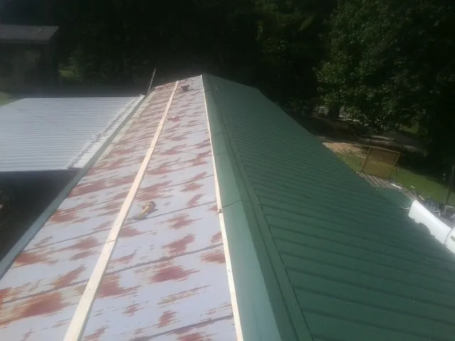 Old rusted panels beside newly installed green metal roofing — Wind Damage Roof Repair by Roofing Brothers in Michigan City