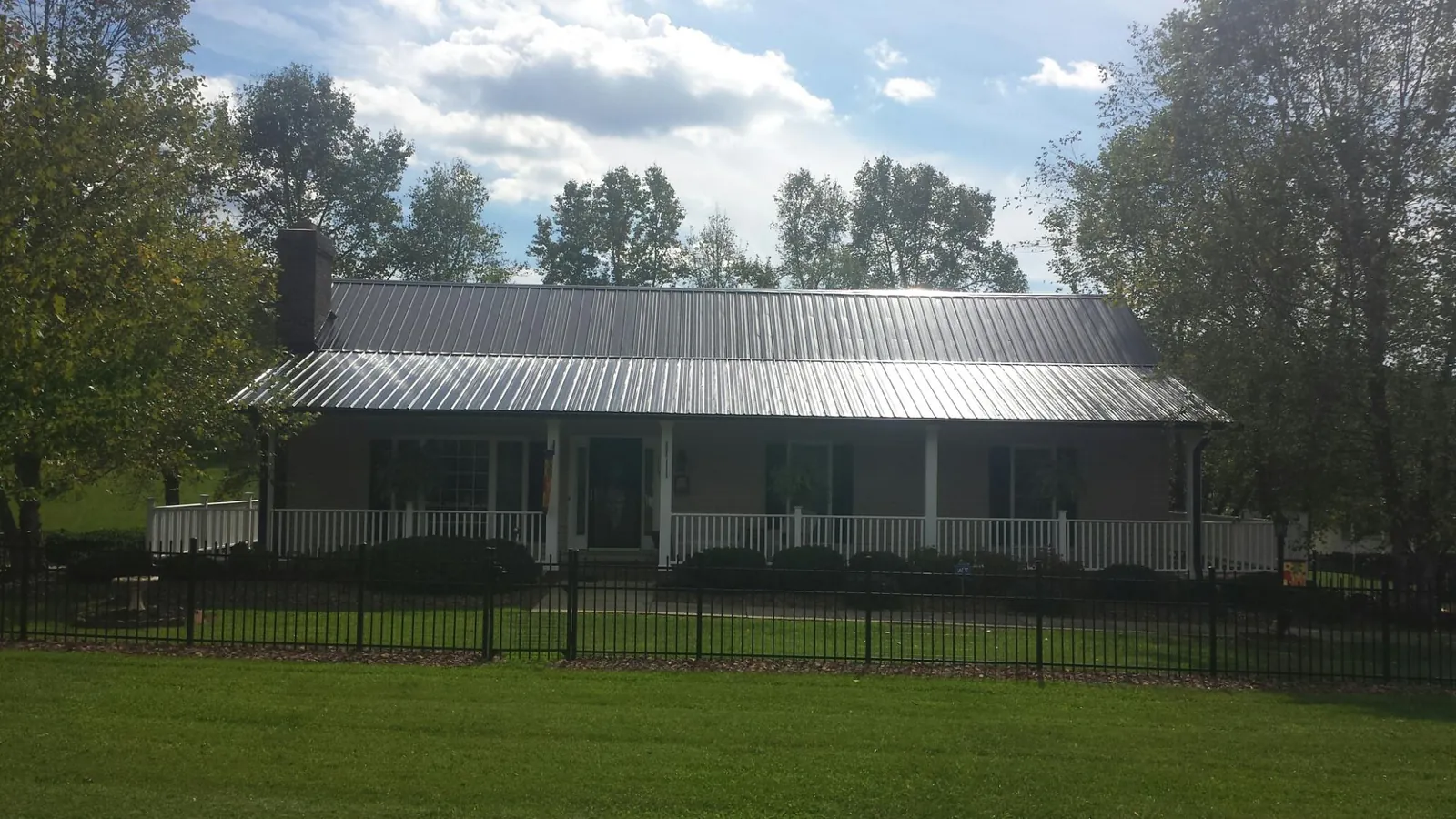 Gray metal roof on a brick ranch with a full width front porch — Gutter Guard Installation work by our crew in Michigan City